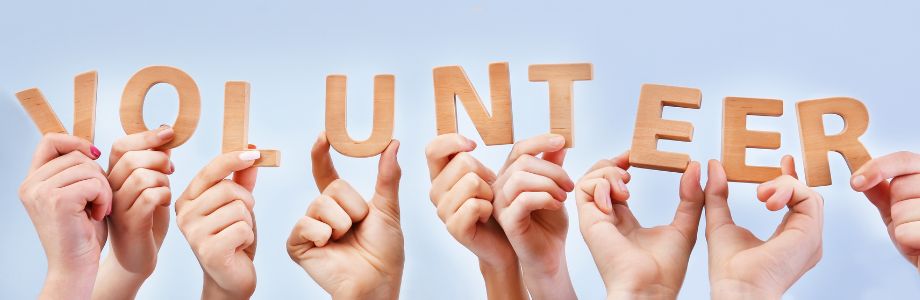 hands holding up wooden letters that spell volunteer